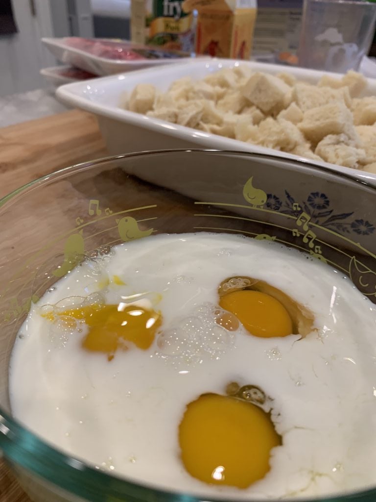 A bowl of eggs next to bread dumpling pieces