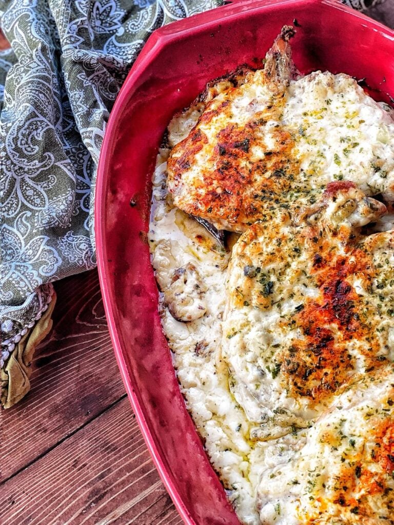 Pork chops with stuffing topping in a red baking dish.