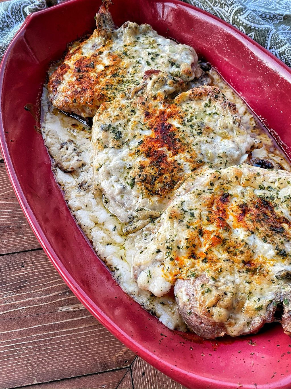 The finished stuffing and gravy pork chops in a red baking dish.