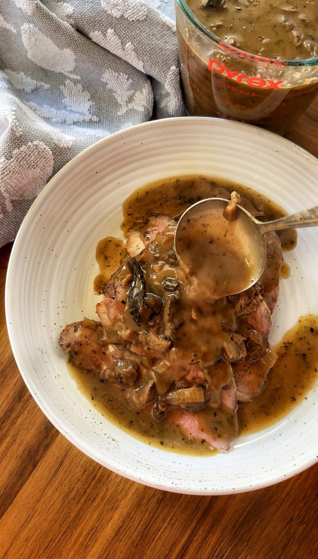 Mushroom gravy being ladled over beef.