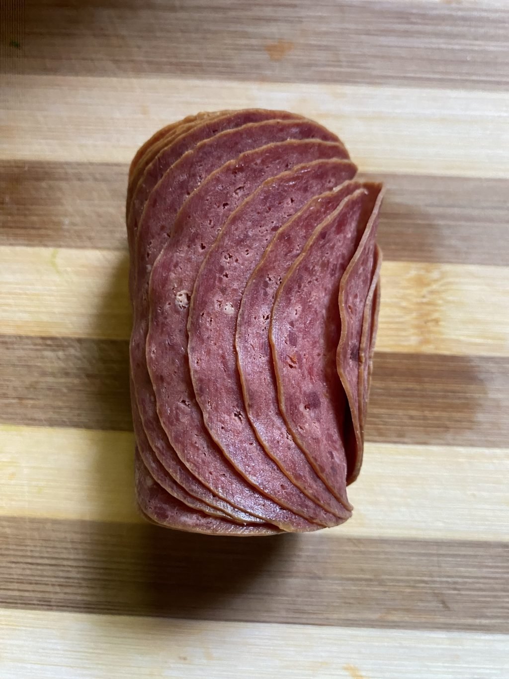 Slices of dried beef on a wooden cutting board.