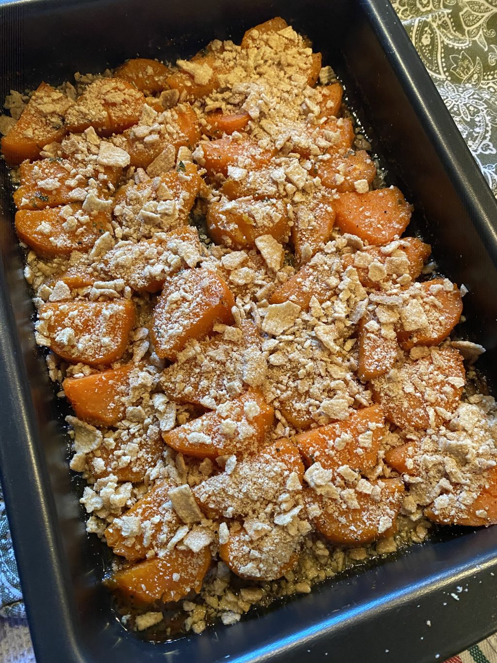 Slices of sweet potato laid out in a baking pan topped with crushed Cinnamon Toast Crunch.