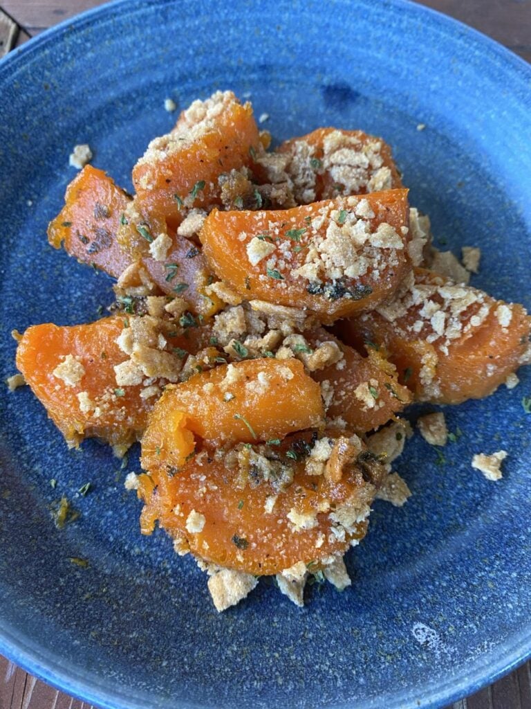 Baked pieces of sweet potato topped with crushed cereal crunch on a blue plate.