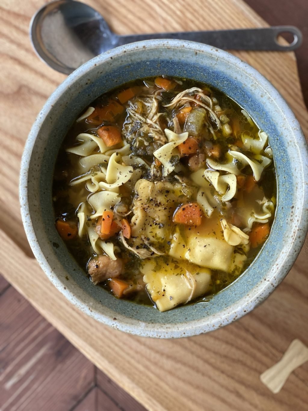 A bowl of chicken noodle soup seen from above.