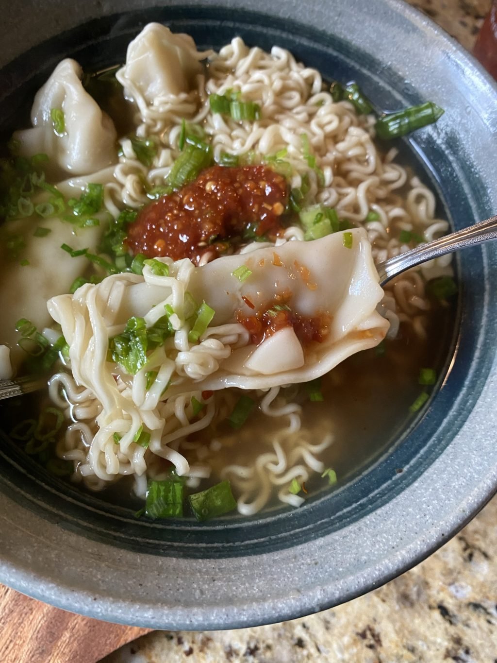 Dumpling noodle soup with a dollop of chili sauce on top.