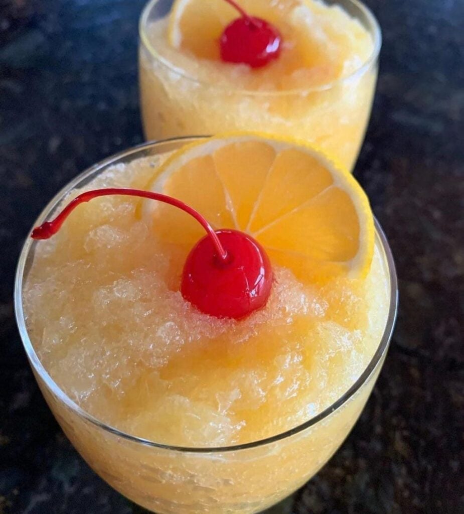 A brandy slush cocktail with cherry and orange wedge on top.