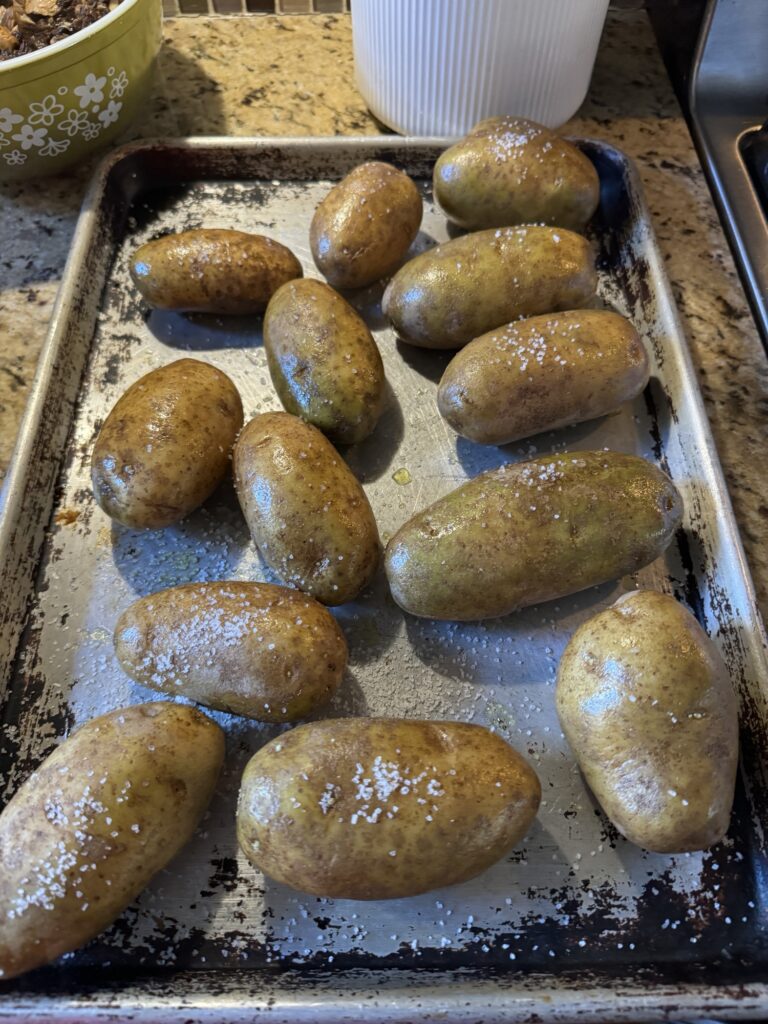 Potatoes topped with oil and sat on a baking pan.