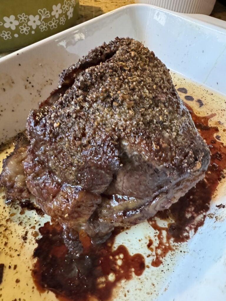 The cooked, seasoned beef roast in a white baking dish.