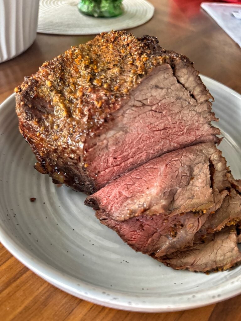 Sliced holiday beef roast on a white plate.
