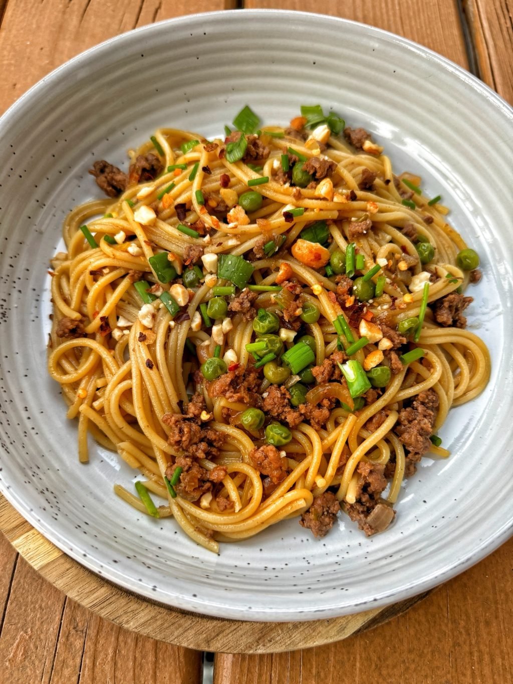Asian Spaghetti Bolognese topped with green onions and crumbled peanuts. 