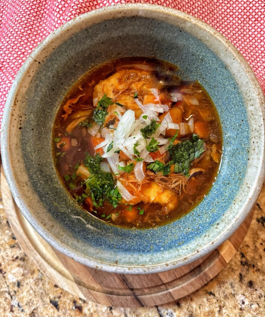 Tamale Soup in a blue bowl topped with diced onion