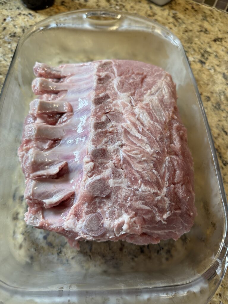 The pork rack roast in a glass baking dish