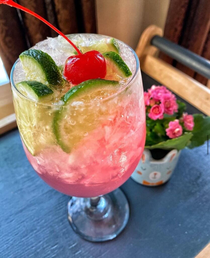 A pantry party drink with slices of lime and a cherry on top