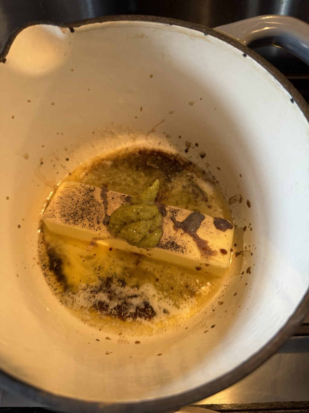 A stick of butter in a pot topped with wasabi paste