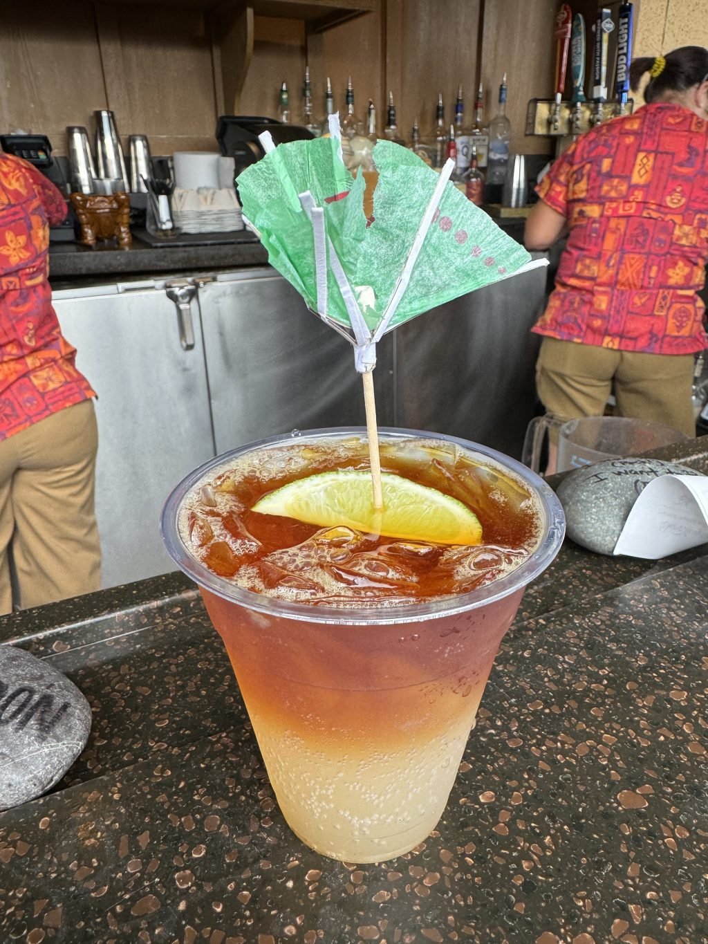 A Tropical Storm cocktail with a broken drink umbrella sitting on a bar