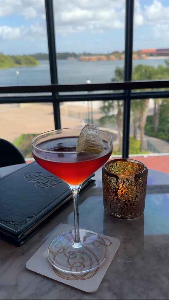 A cocktail on a table in front of a window overlooking the view of outside