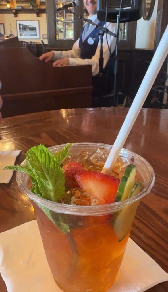A Pimm's Cup on a table in front of a man playing piano