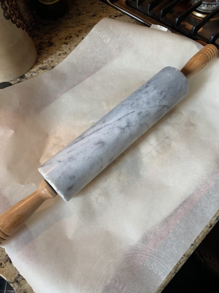 Rolling pin on parchment paper over dough