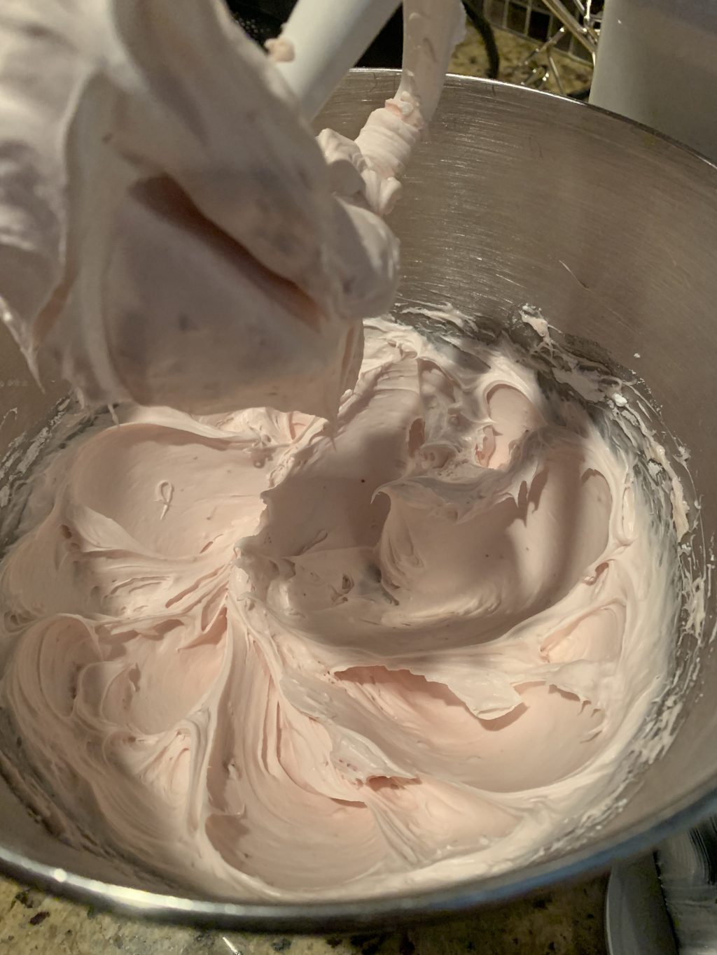 The cream cheese being blended in a bowl mixer