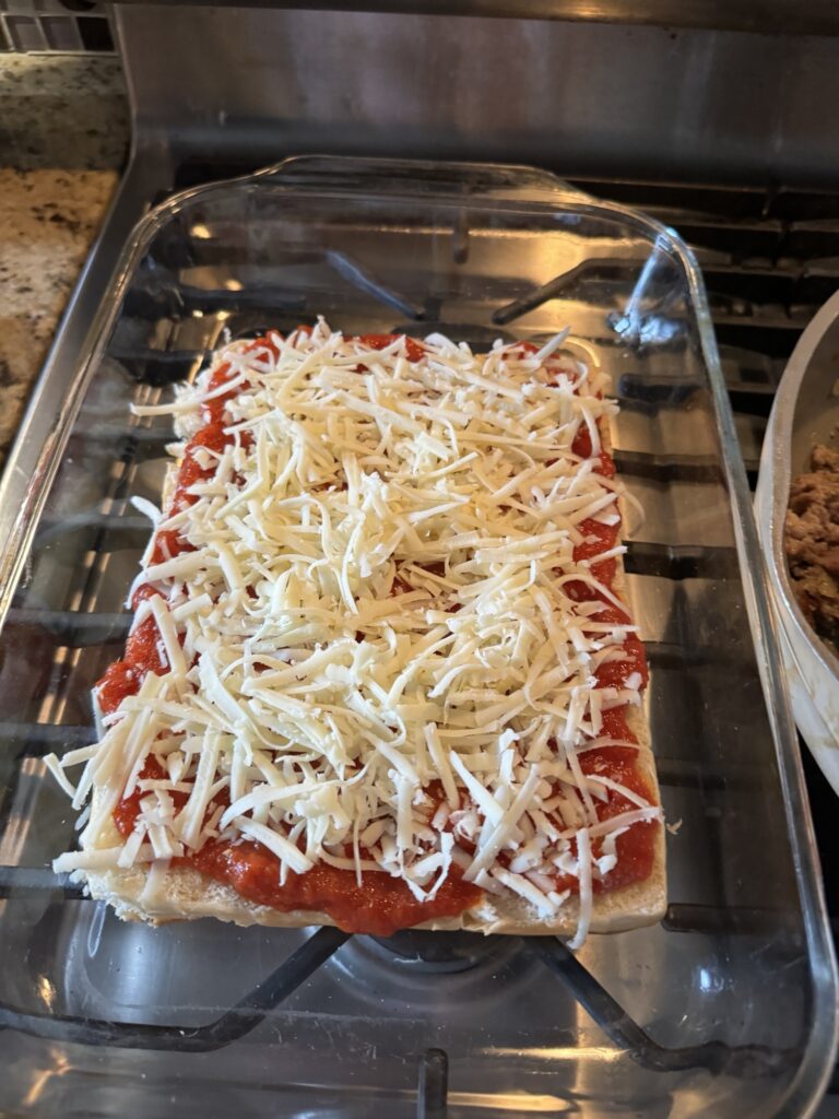 The sliced buns topped with marinara and shredded cheese