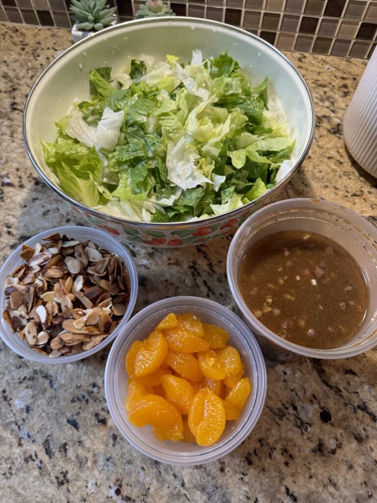 The salad, nuts, oranges, and dressing in separate bowls