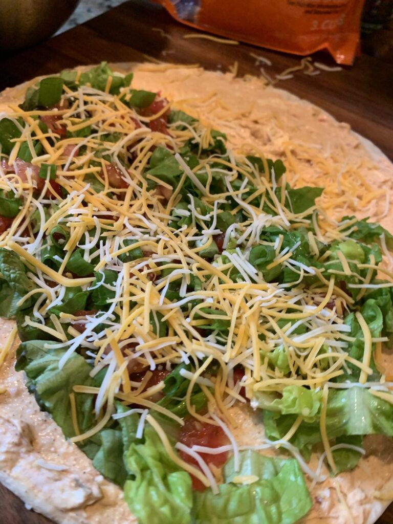 Shredded cheese and shredded lettuce on tortilla