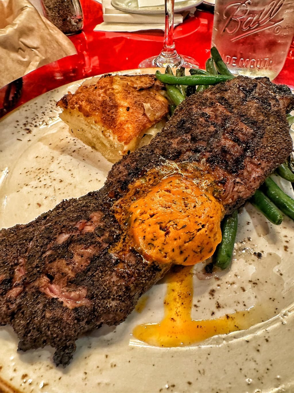 Char crusted NY strip steak with cowboy butter, potatoes gratin, and green beans
