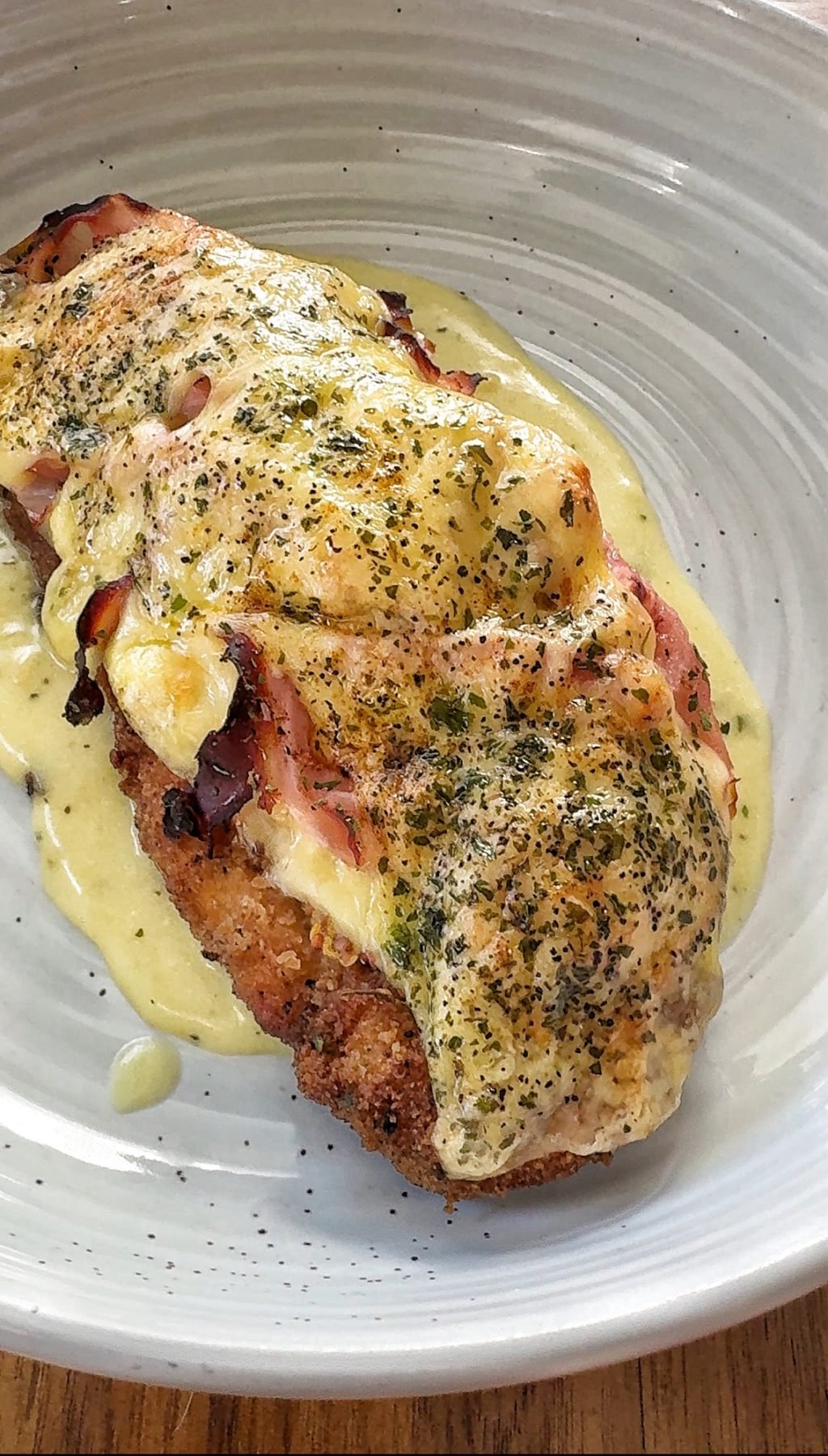 A chicken cutlet and ham covered in melted Swiss cheese