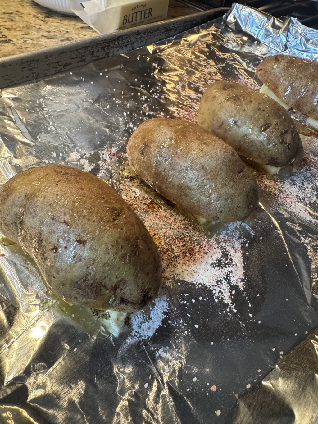 The potato halves face down on the seasoned butter pats before going in the oven