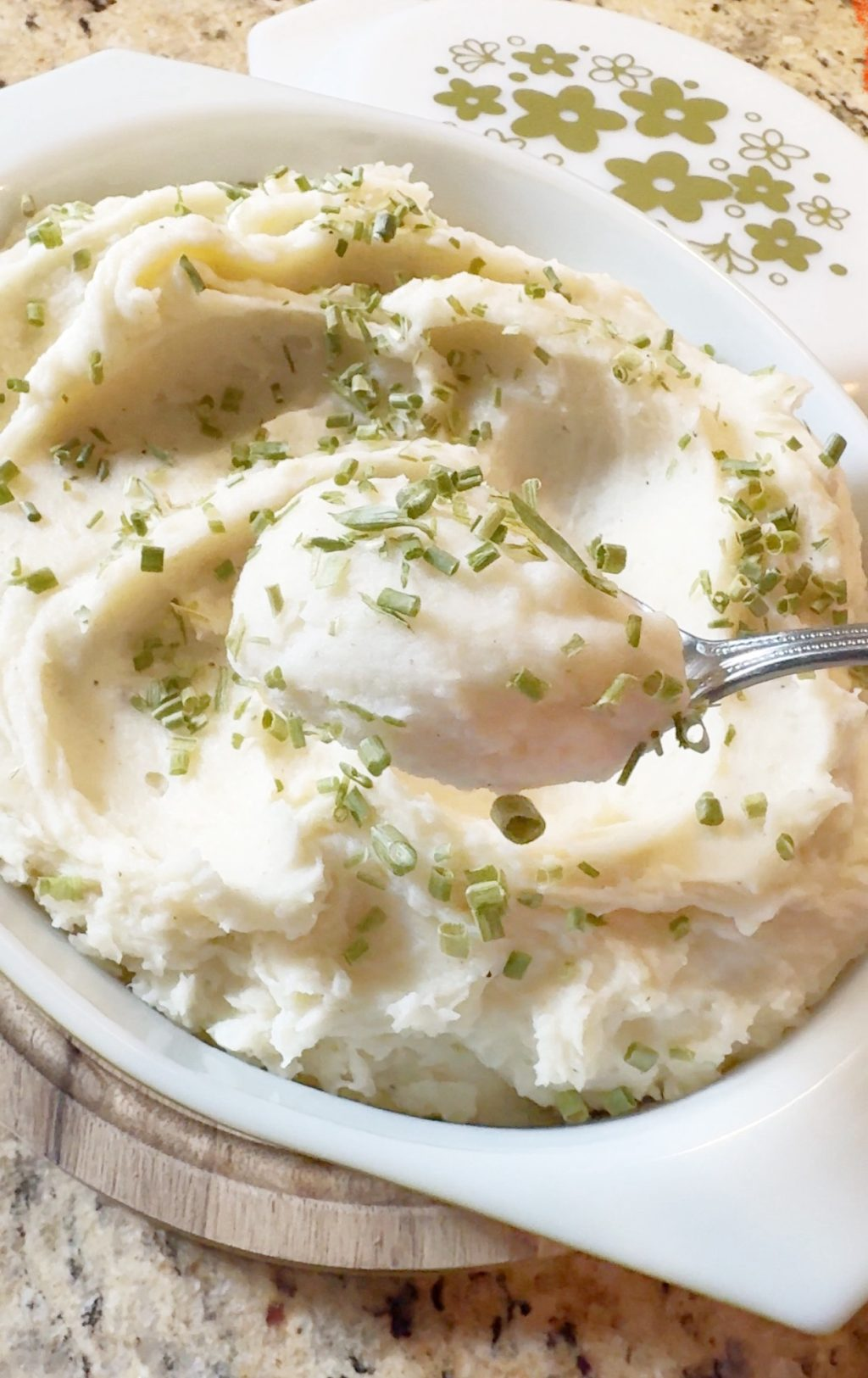 A spoon of mashed potatoes with green onion