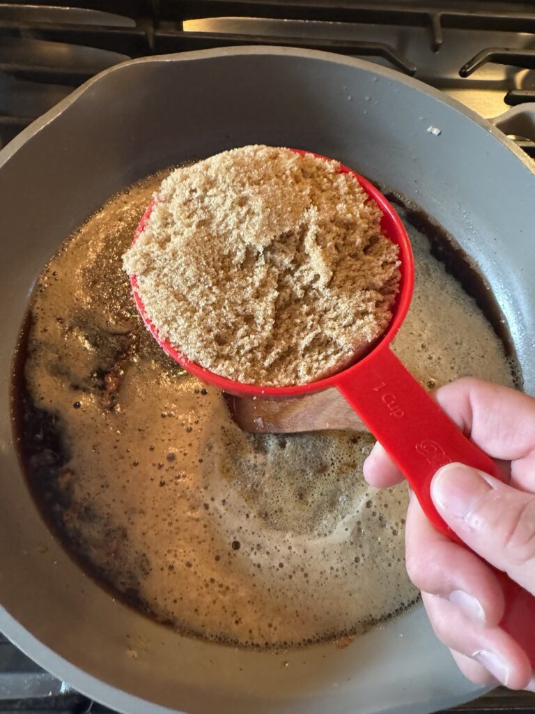 A measuring cup of brown sugar over the Guinness Sauce.