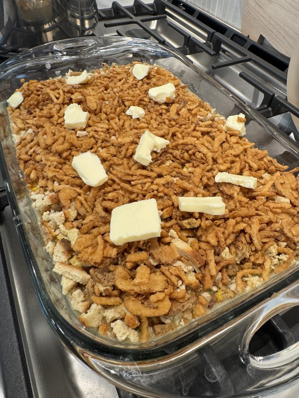 Casserole mixture topped with crunchy bits and butter pats