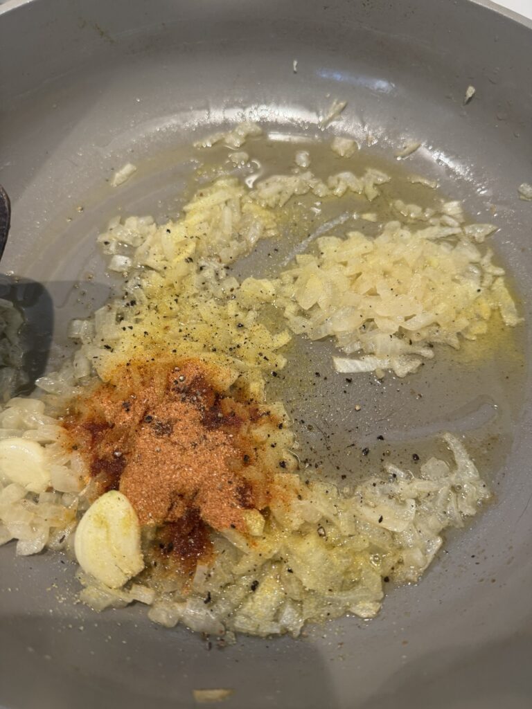 The seasonings, onion, and garlic sizzling up in a pan