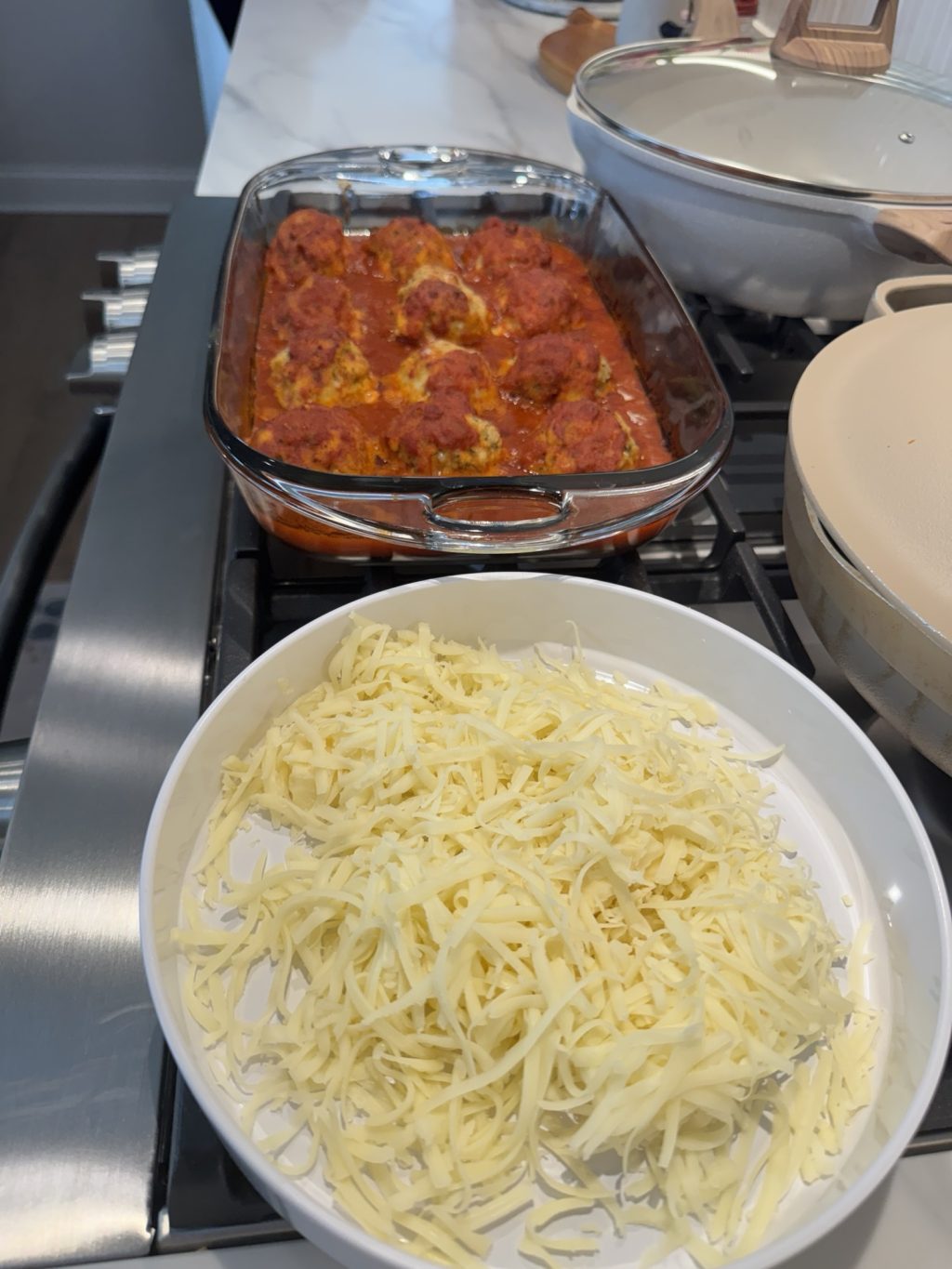Shredded cheese in a bowl in front of the meatballs