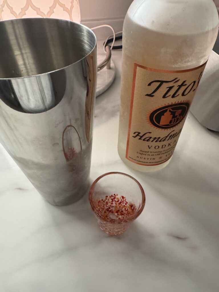 Tito's vodka, a cocktail shaker, and a shot glass