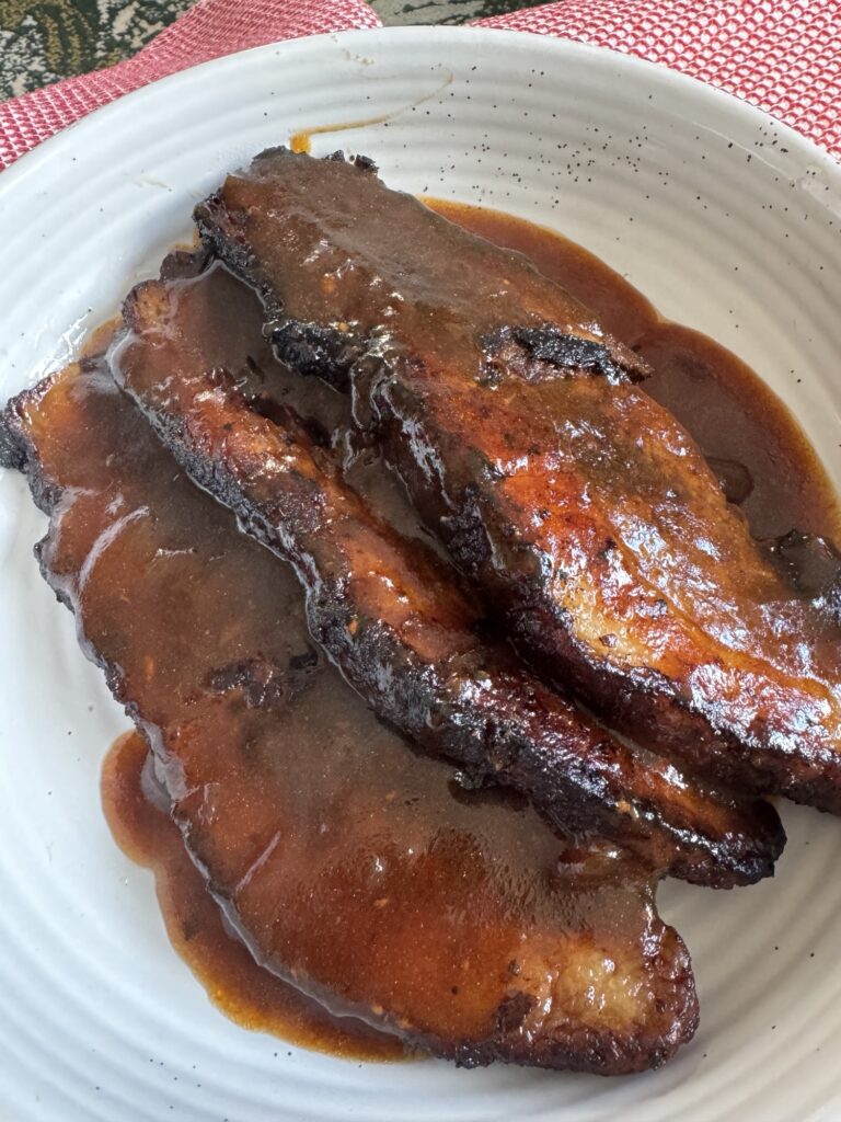 The finished brisket on a plate, covered in gravy