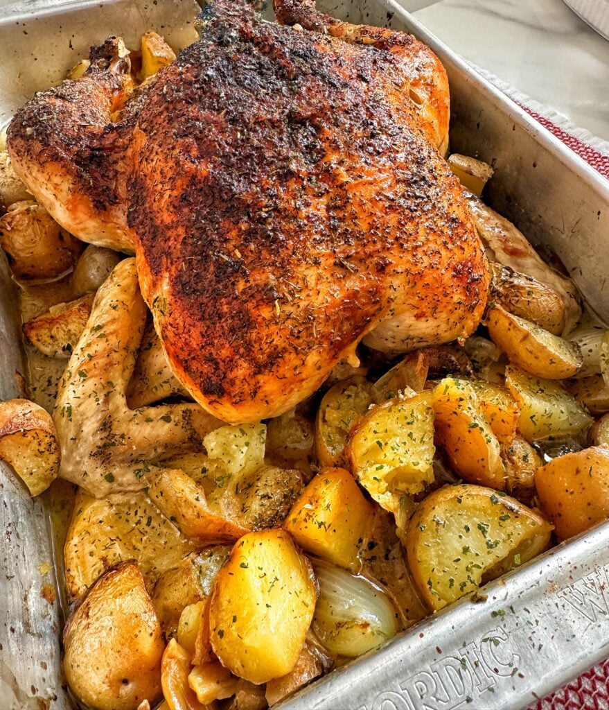 The finished roast chicken over potatoes