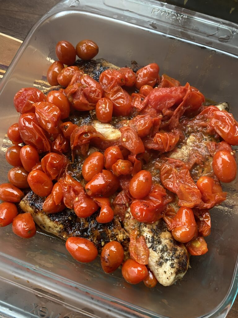 The tomatoes from the foil over chicken in a baking dish