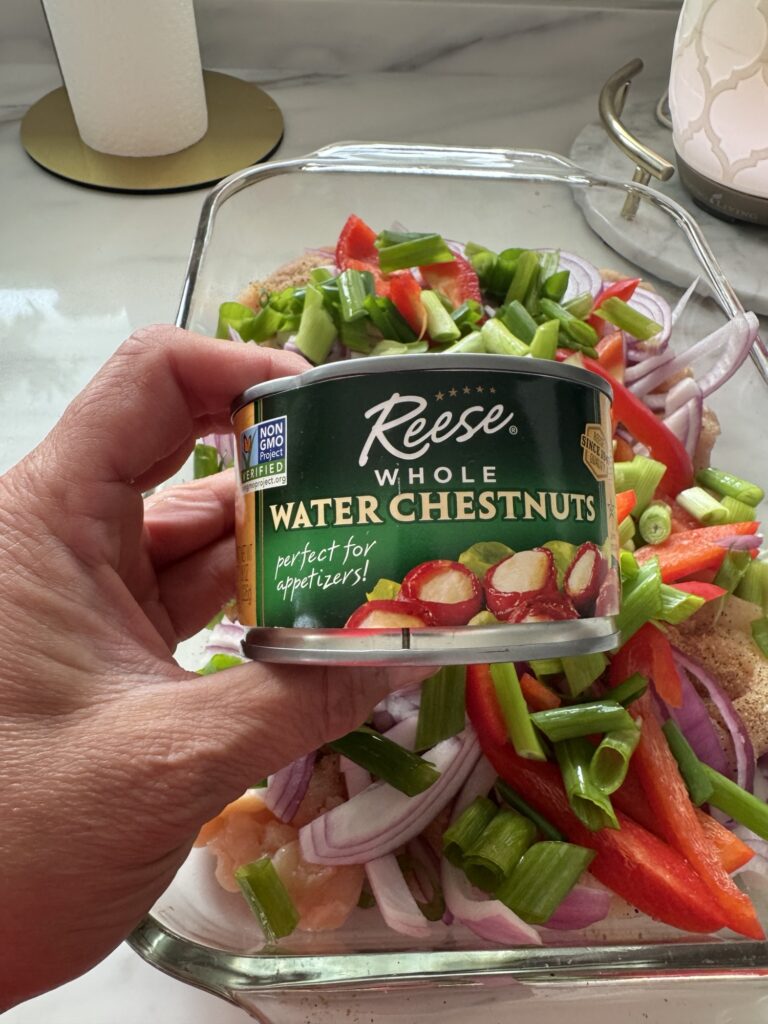 A can of chestnuts over the chicken and veggies in the pan