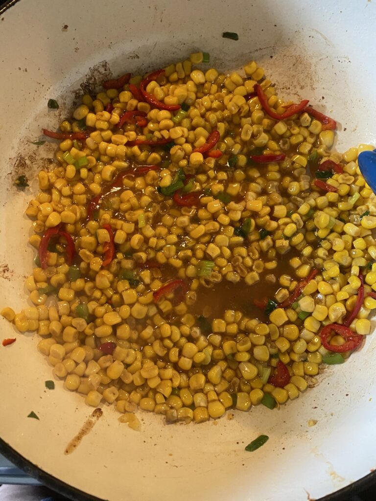 Corn and peppers cooking in a pan