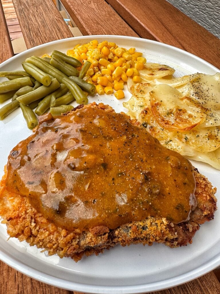 Oven fried pork chop with gravy, potatoes, corn, and green beans