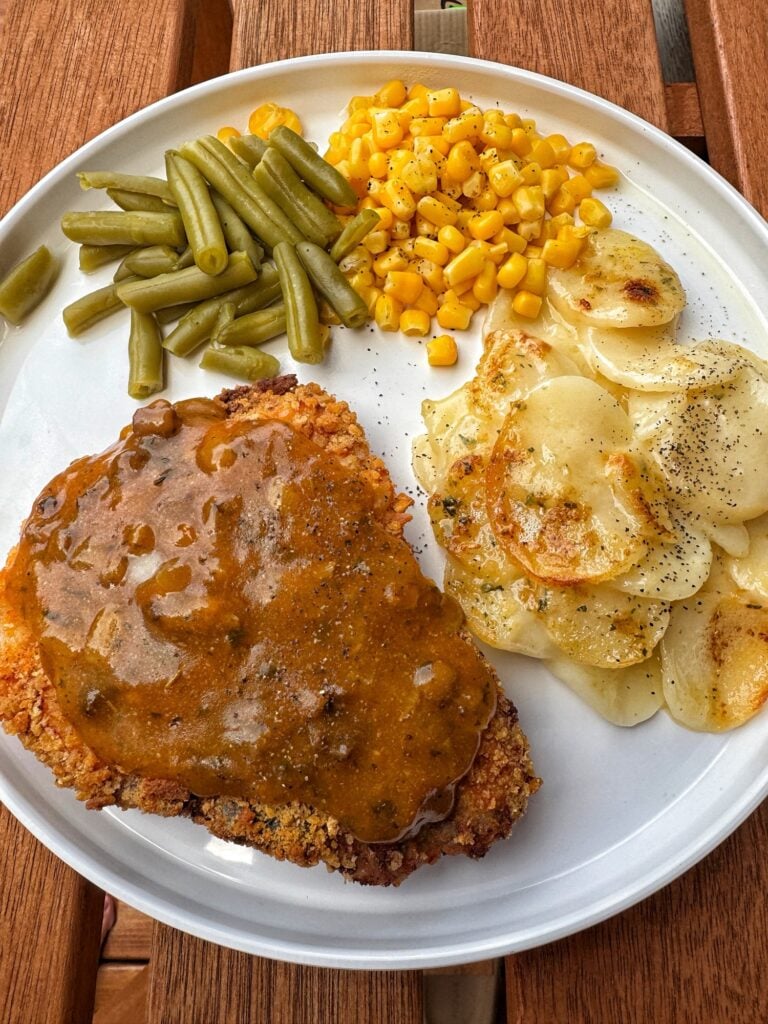 Oven fried pork chop with gravy, potatoes, corn, and green beans