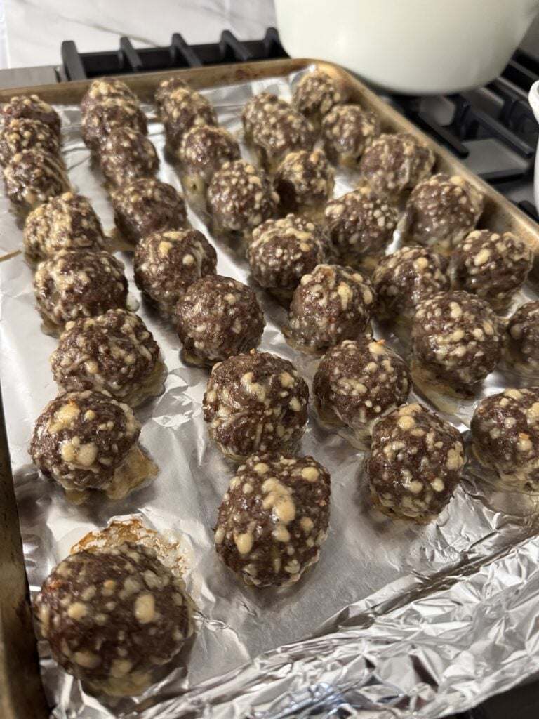 The cooked meatballs on a baking sheet before going in the sauce